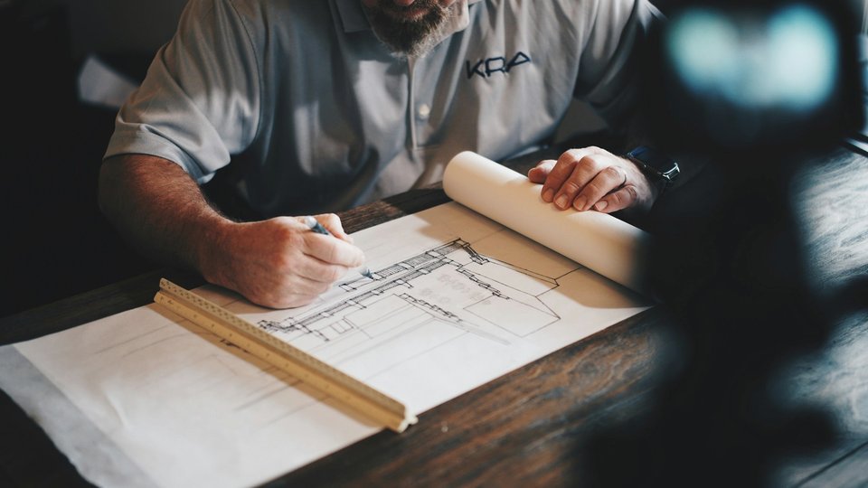 Mains dessinant un plan avec un crayon et une règle