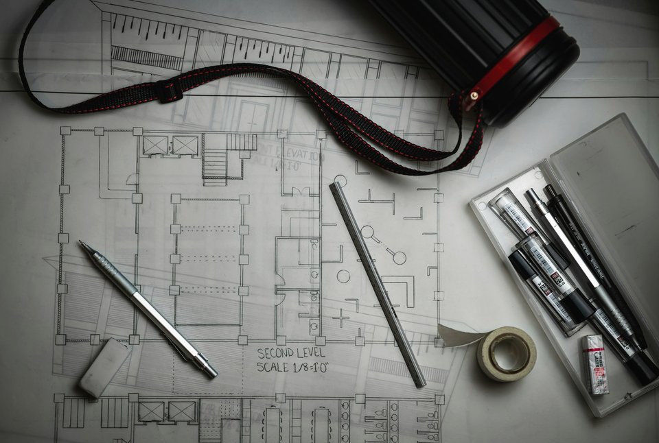 Plans d'architecte sur un bureau avec crayons et règle métallique